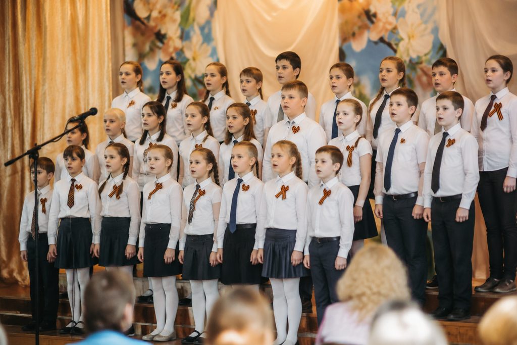 Класс поёт свой гимн на сцене школьного конкурса, дружный коллектив
